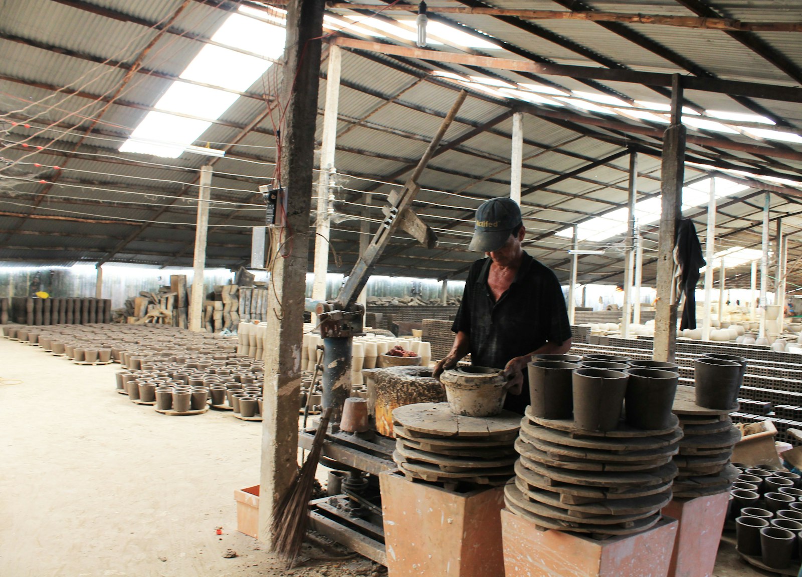 Pottery factory worker surrounded by ceramic pots